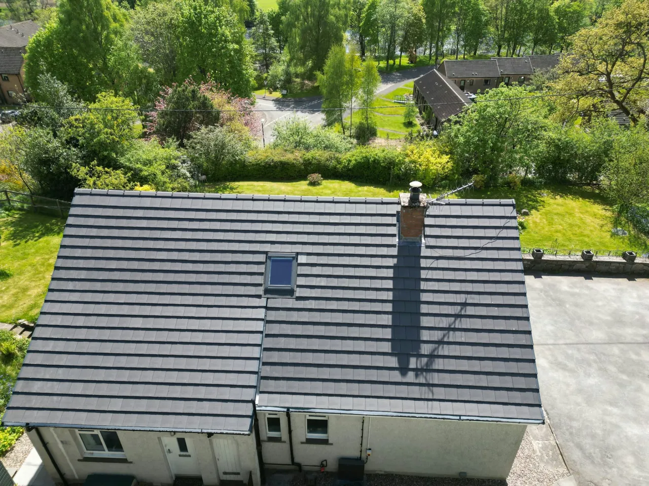 Aerial view of a new grey tiled roof with rooflight and chimney on a Perthshire bungalow