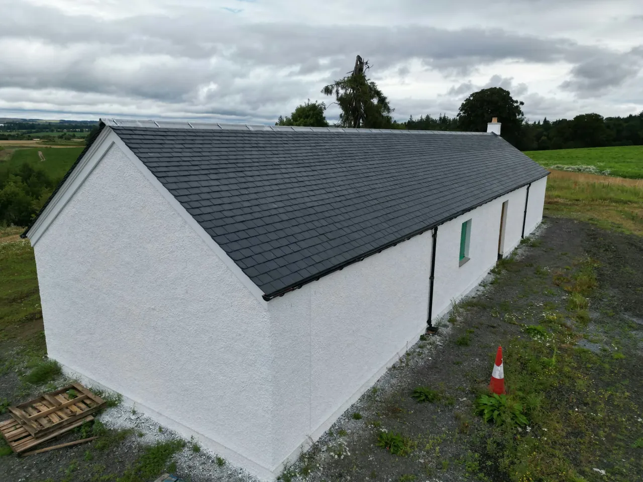 Gable end of a cottage with a new slate roof and black guttering