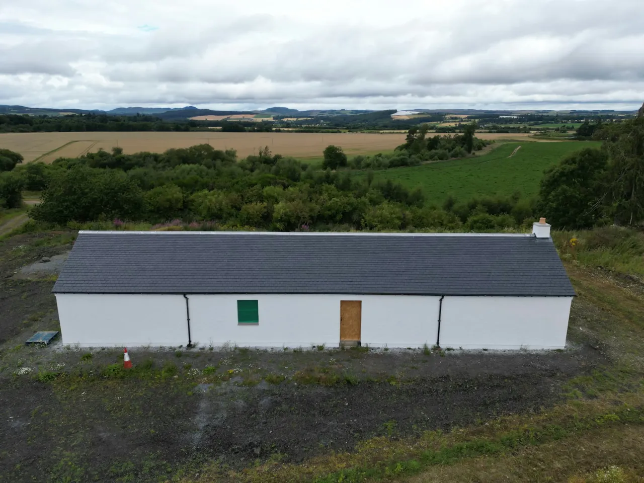 New slate roof on a white cottage with farmland and hills beyond
