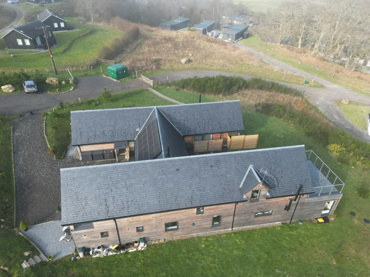Aerial view of a slate-roofed timber-clad house with solar panels