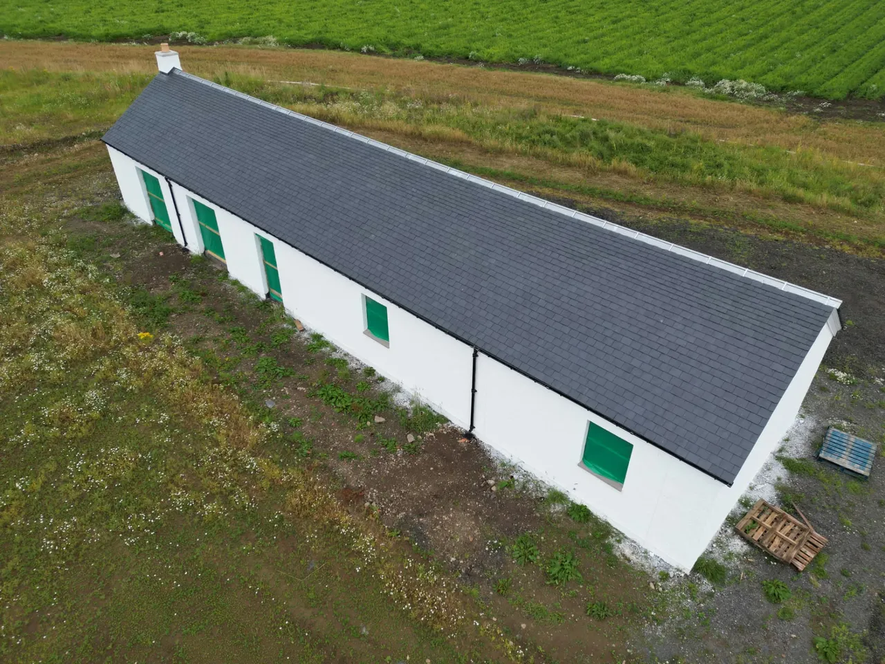 Drone view along a newly slated cottage roof beside farm fields