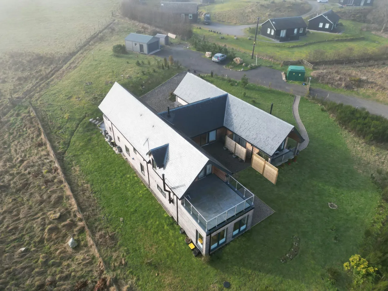 Slate roofs and a flat roof terrace on a timber-clad home in the countryside